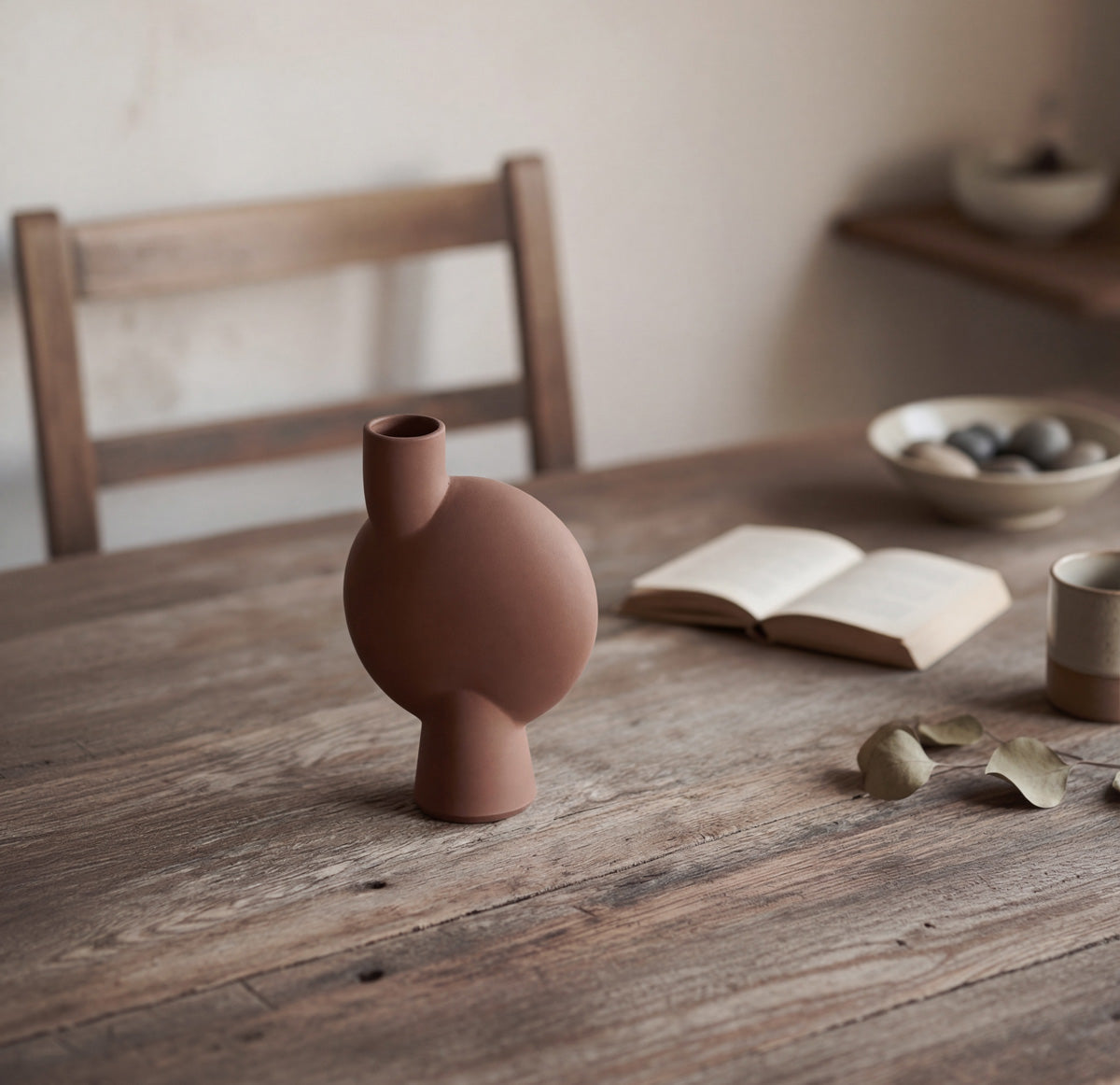 Sphere vase in Almond on a table with an open book 
