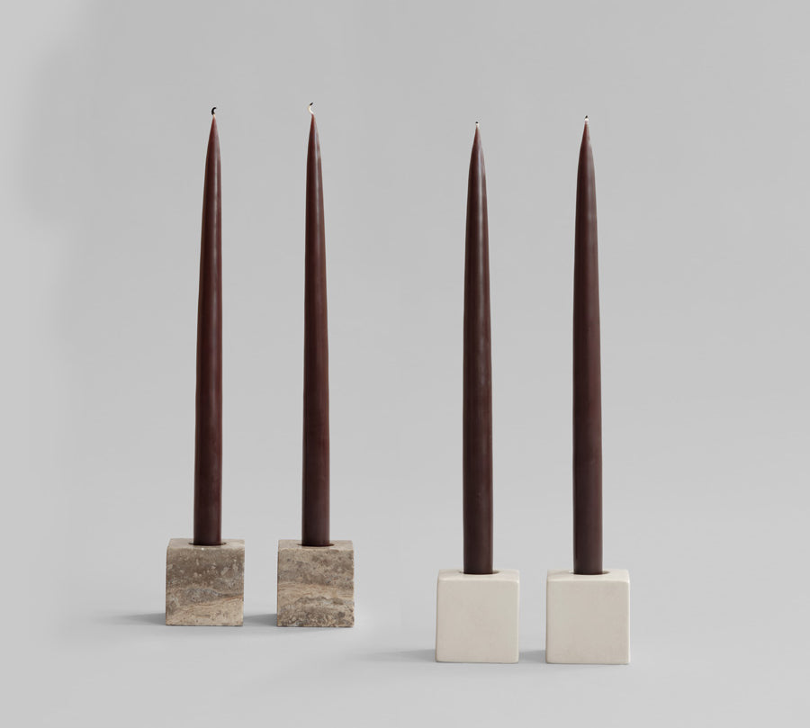 Four dark brown candles in square Cube candle holders on a light gray background