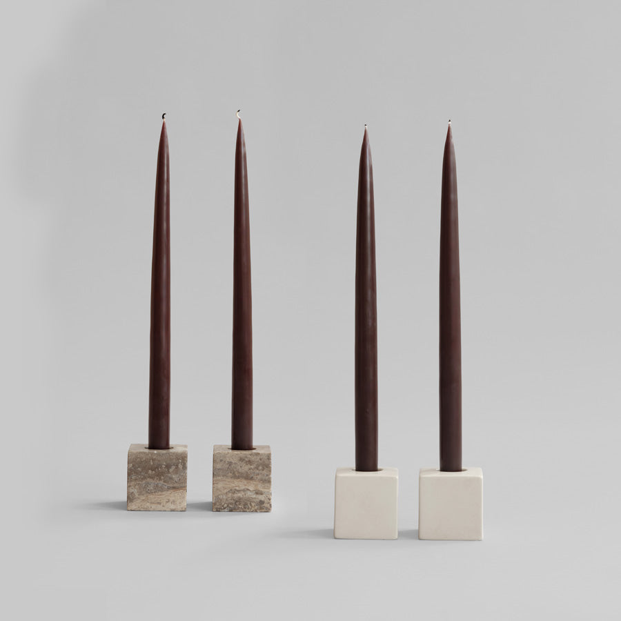 Four dark brown candles in square Cube candle holders on a light gray background