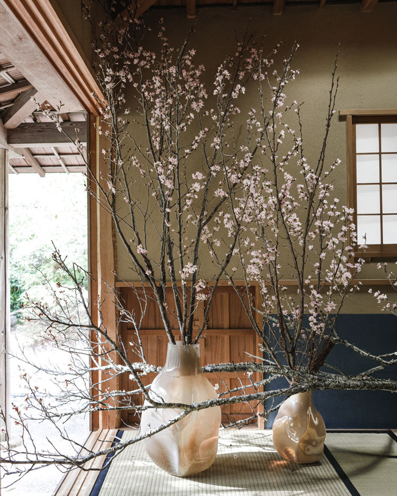 Decorative branches by Hikaru Seino in Bakku vases on a table with a traditional Japanese room background