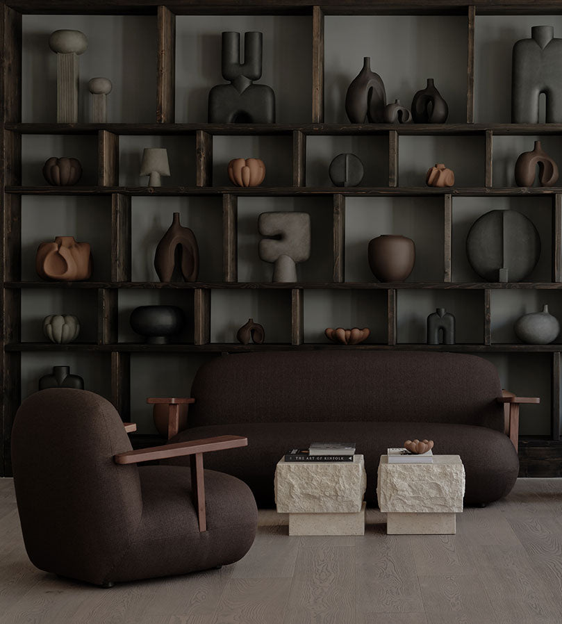 Modern living room with dark brown Toe sofa, Toe armchair, and bookshelf filled with 101 Copenhagen Vases and decorations.
