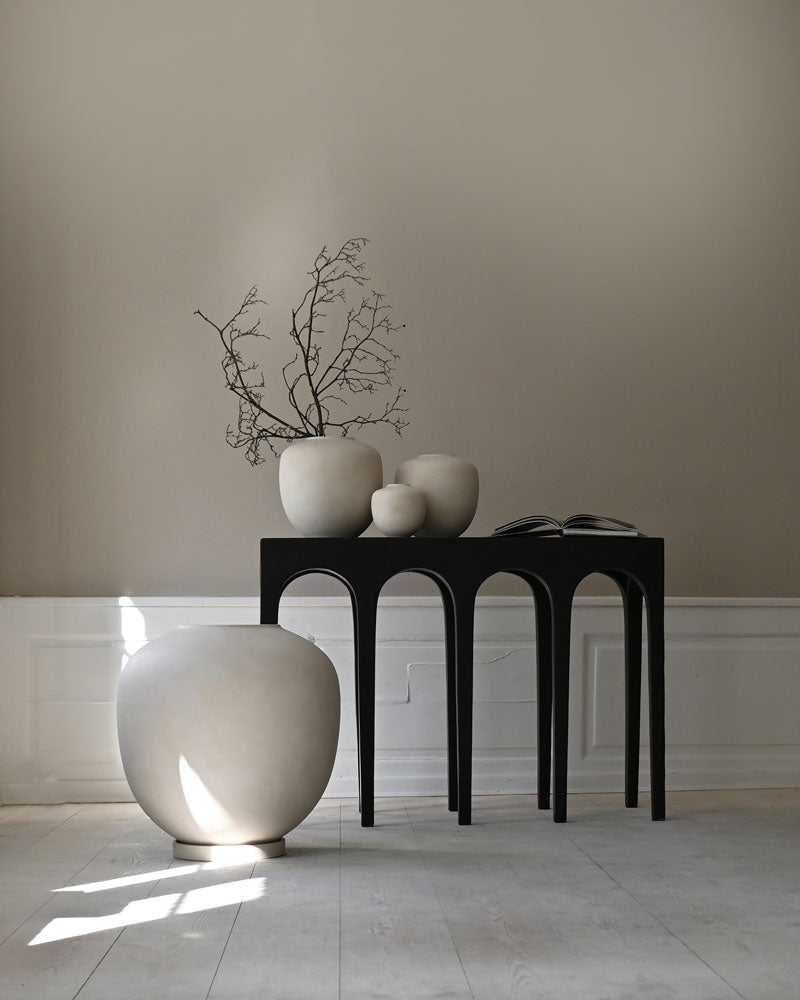 White ceramic Sunao vases and a plant pot on a Bow console table against a beige wall