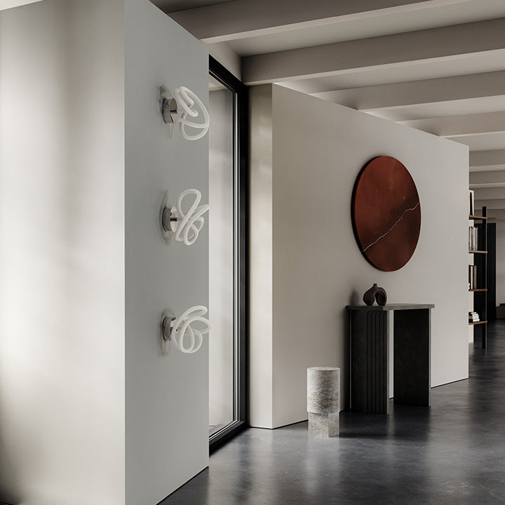 3 Ghost ceiling lamp on wall next to an Arc console Ni vase and Column table in Silver Travertine