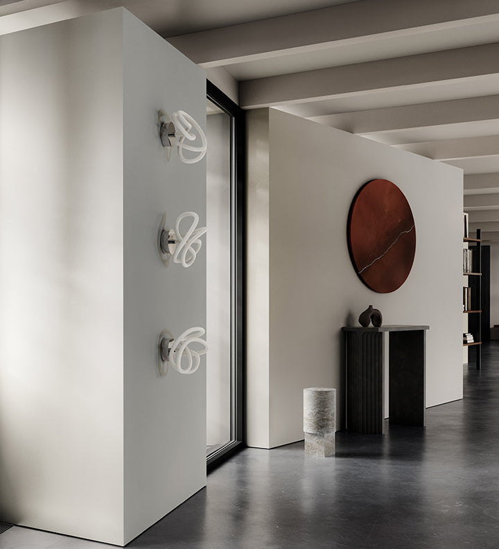 3 Ghost ceiling lamp on wall next to an Arc console Ni vase and Column table in Silver Travertine